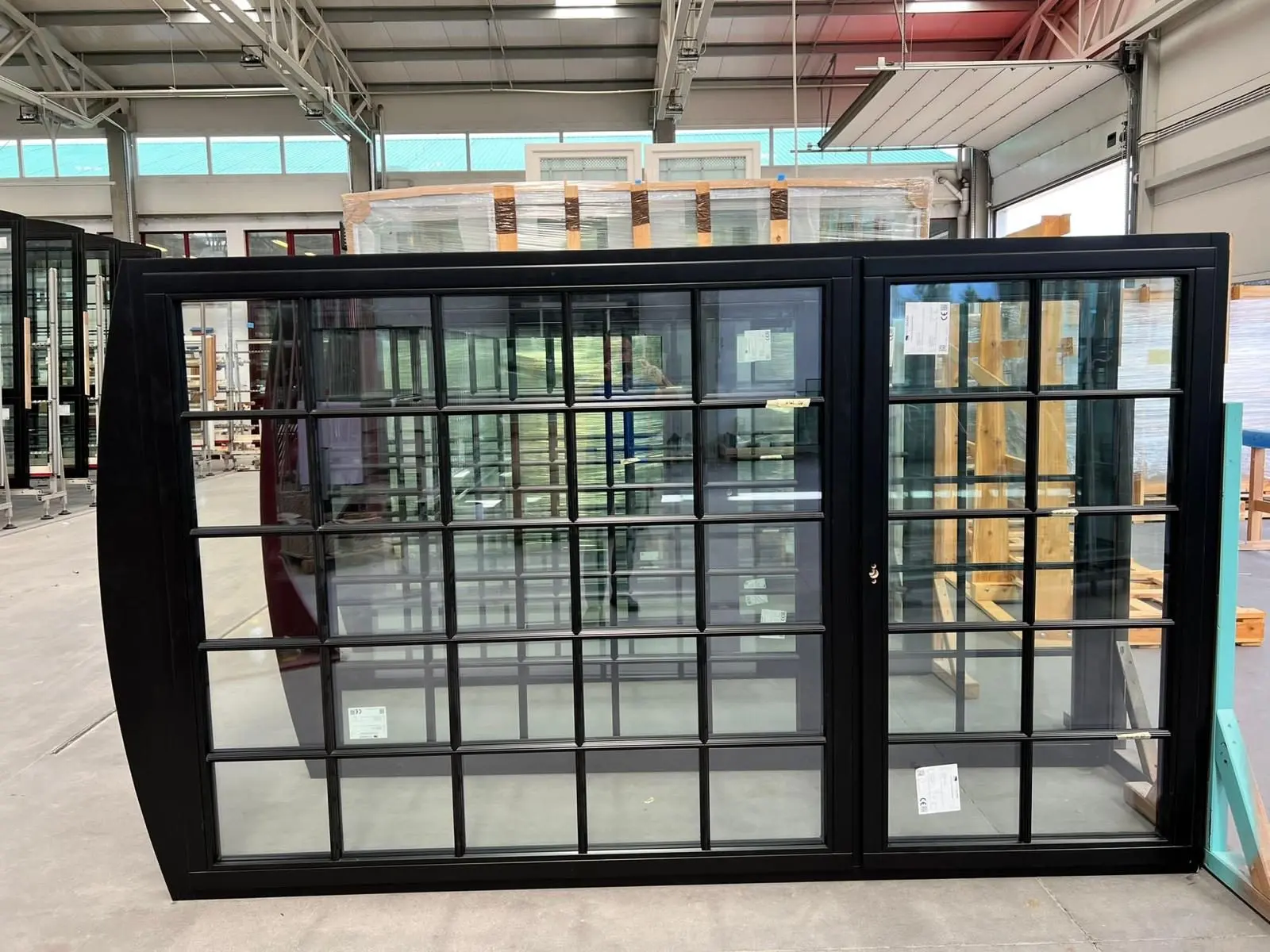 Dark uPVC tilt-and-turn window units standing in a European factory before shipping