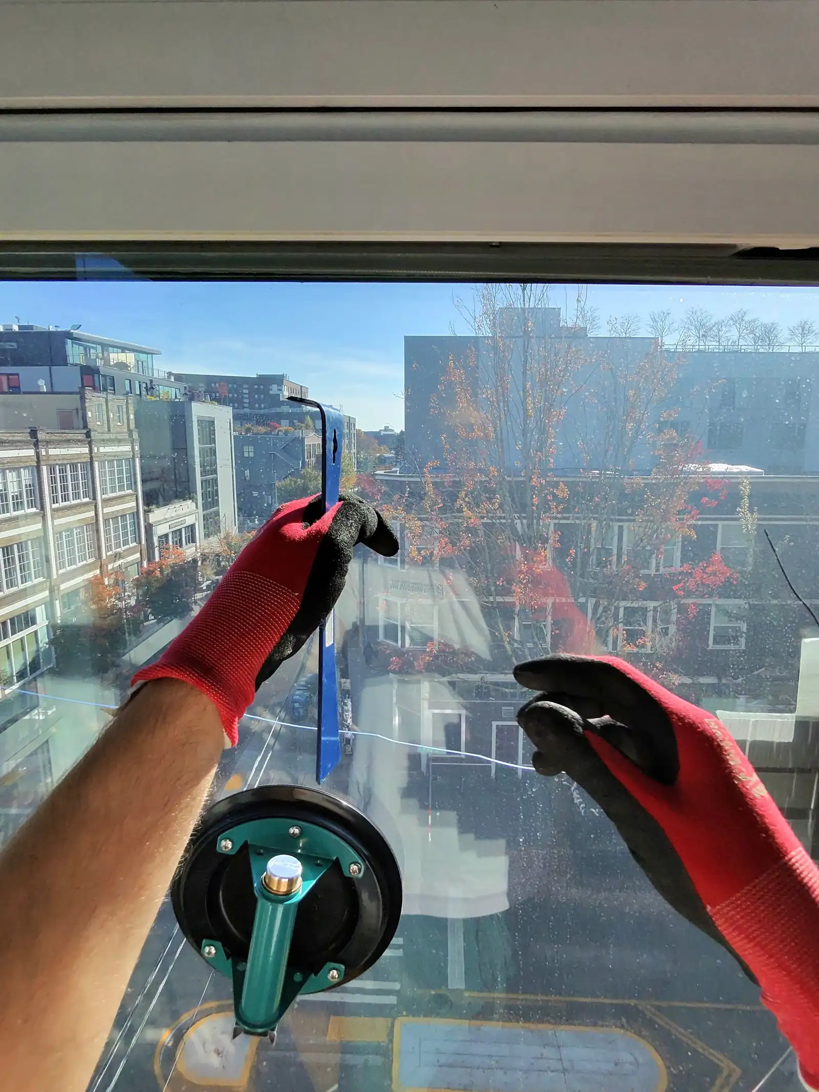 Lifting a new glass unit into a tilt-and-turn window with a suction cup, Capitol Hill, Seattle