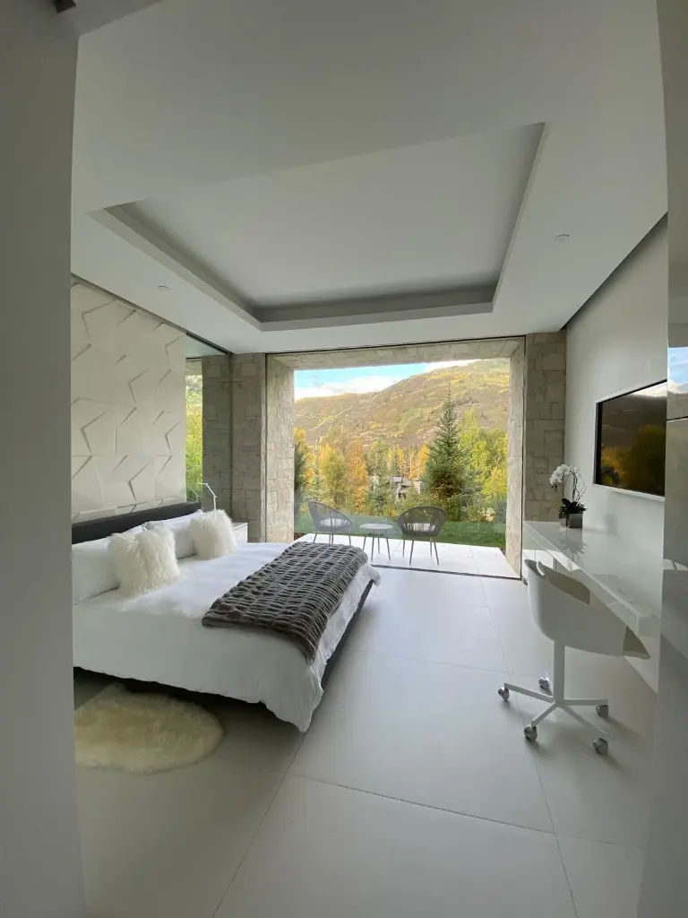 Bedroom and desk beside a large opening onto a mountain view