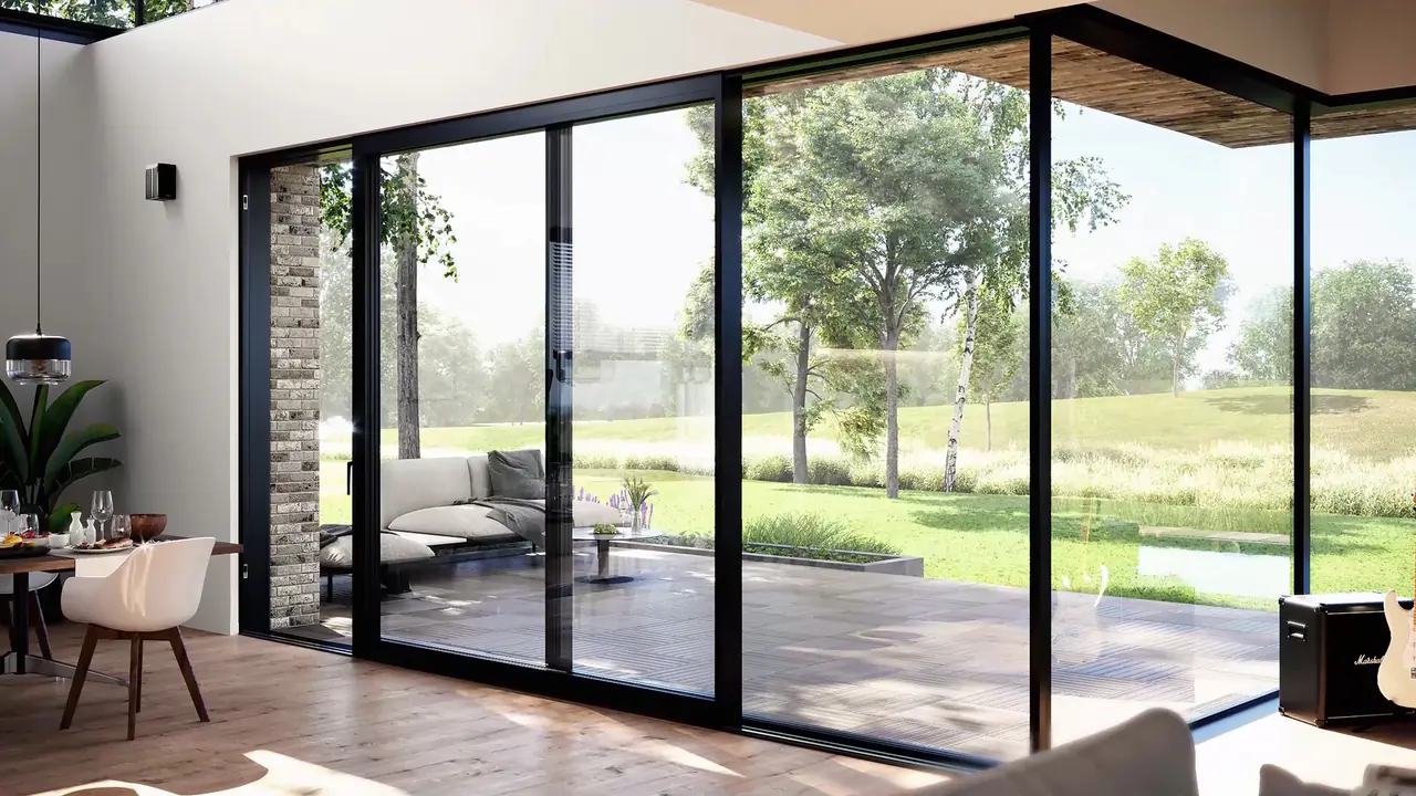 Black-framed floor-to-ceiling sliding glass wall opening a modern living room onto a deck and garden