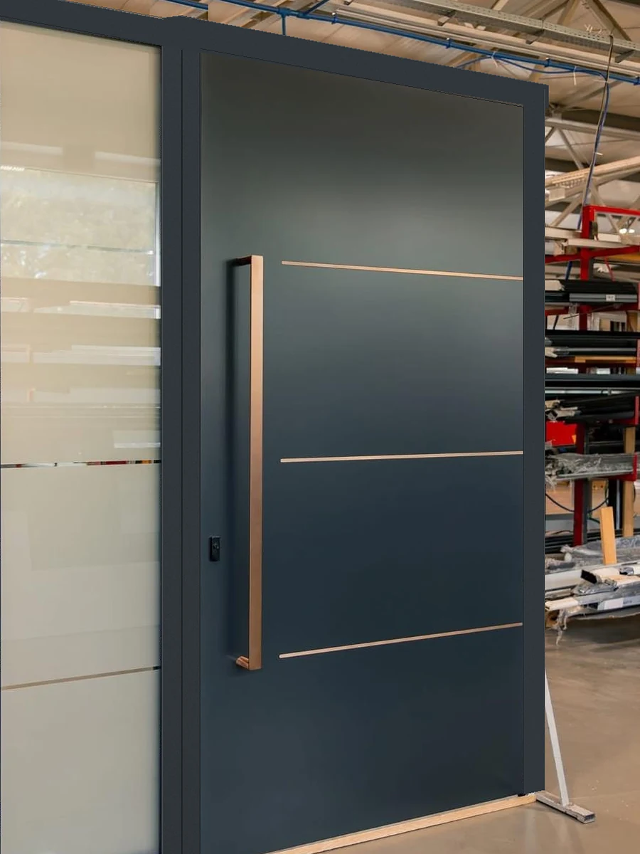 Modern dark slate aluminum pivot entry door with a long copper pull handle, copper inlay lines and a frosted glass sidelight