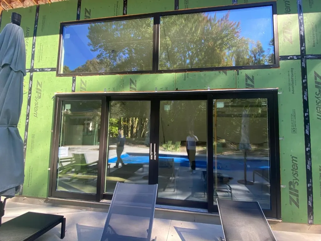Black aluminum-clad Synergic windows and a sliding glass door during construction