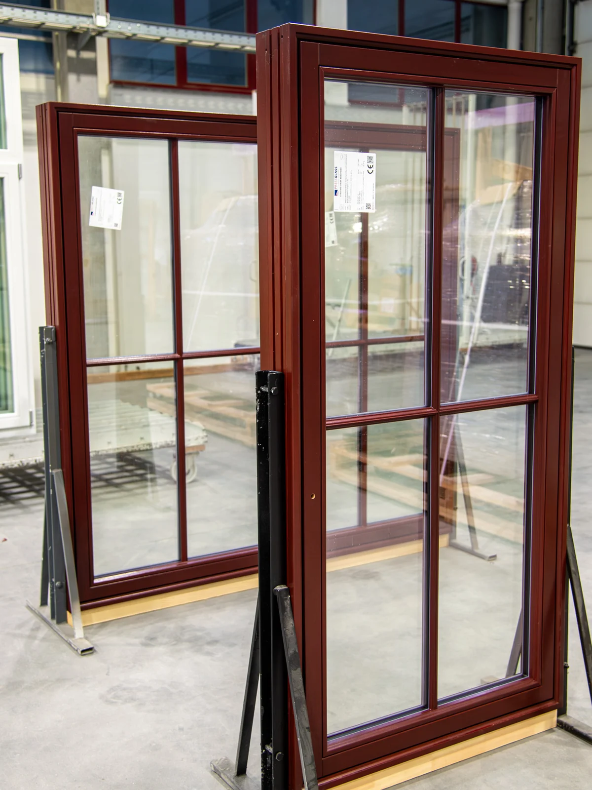 Atlantis wood windows, dark-stained, with divided lites, standing at the factory before shipping