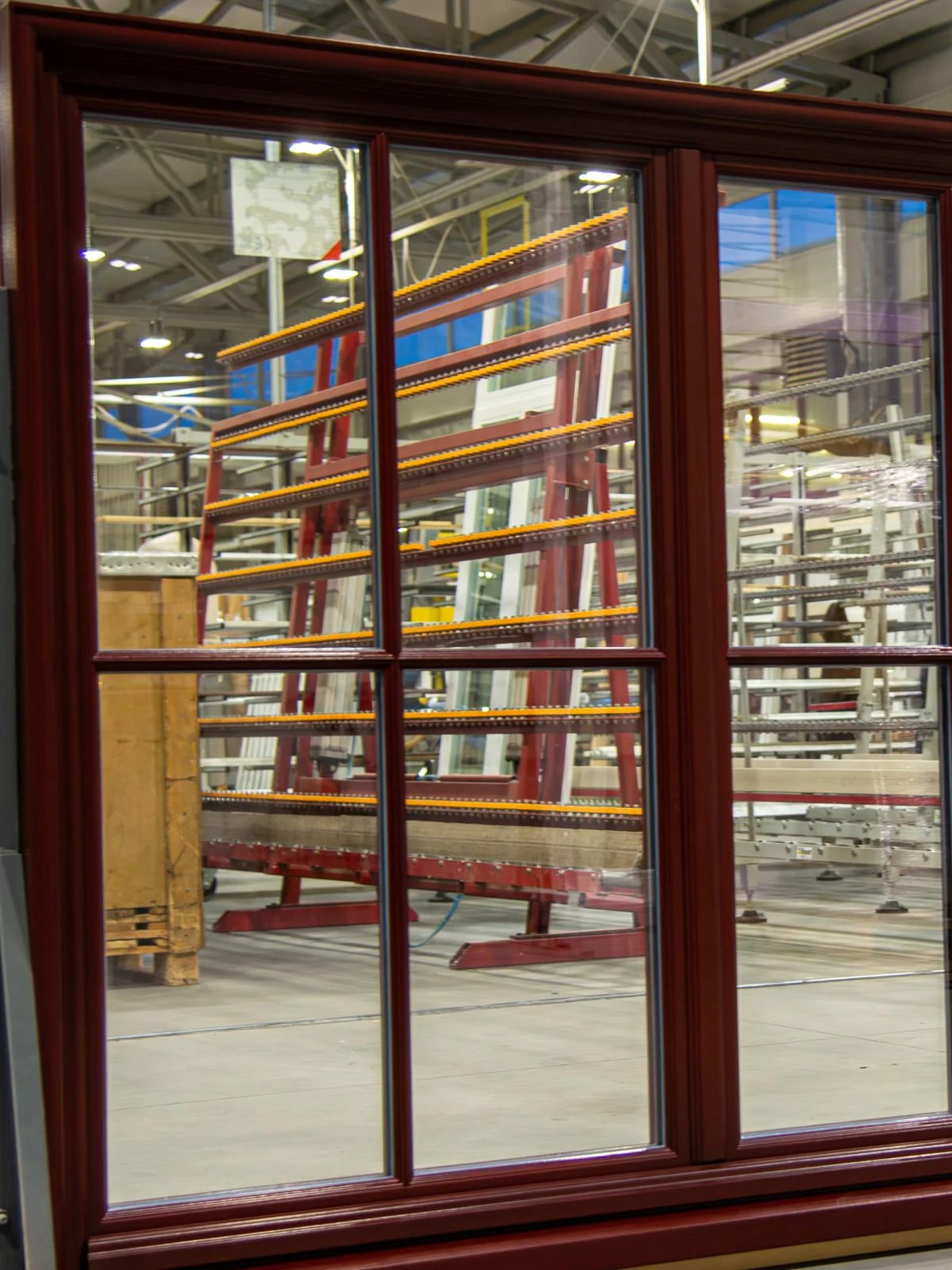 Atlantis wood windows, dark-stained, with divided lites, on a factory rack before shipping