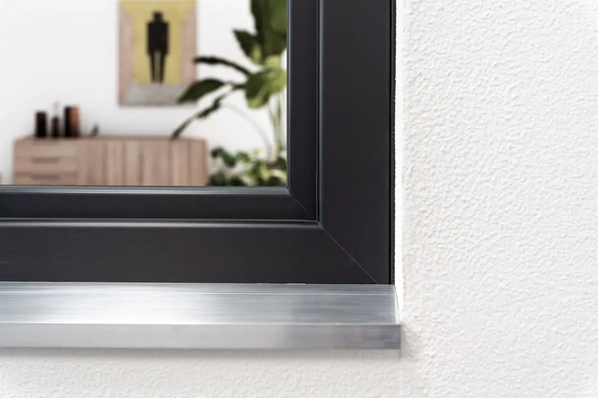 Anthracite P-700 uPVC window corner with an aluminum sill against a white render wall