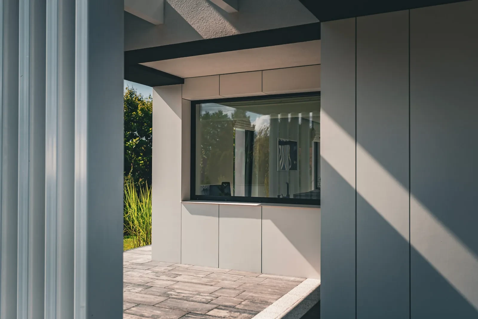 Large dark-framed fixed window on a modern house with grey cladding