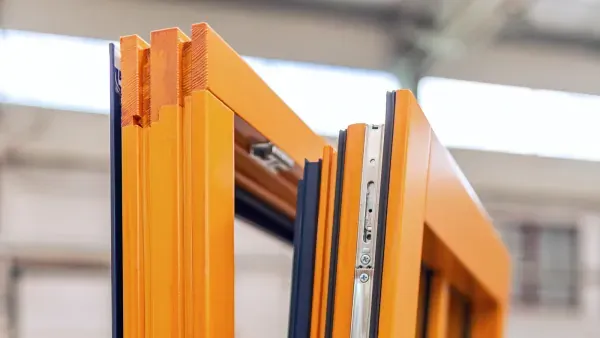 Wood tilt-and-turn window sash open at the factory, showing the multi-point locking hardware along the edge